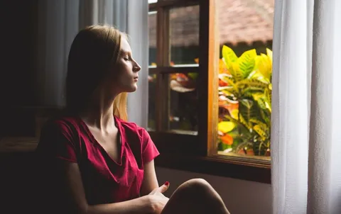 Frau sitzt in ruhiger Umgebung und praktiziert Achtsamkeitsmeditation zur Stressreduktion