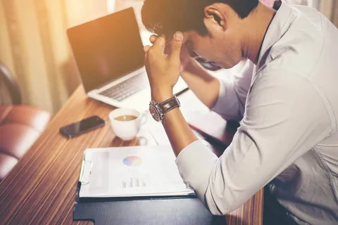 Erschöpfte Person am Schreibtisch – Burnout Prävention durch Stressmanagement und Selbstfürsorge
