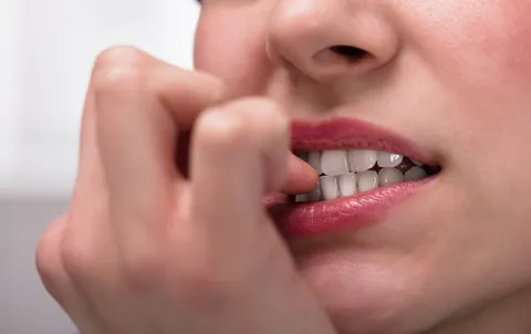 Person kaut nervös an Fingernägeln – Stresssymptom Onychophagie erkennen und behandeln