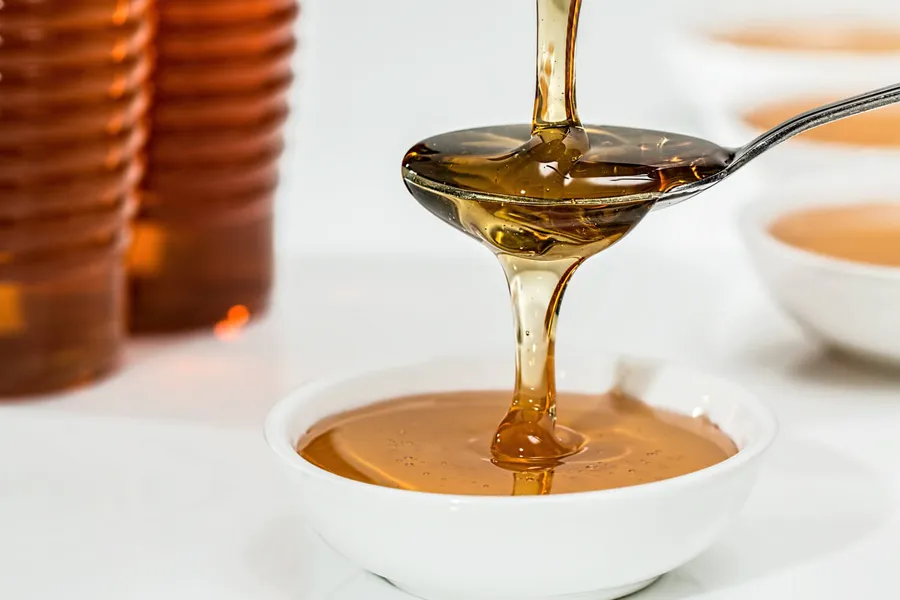Glas Manuka Honig neben einer Bienenwabe – natürliche Stärkung des geschwächten Immunsystems bei Stress
