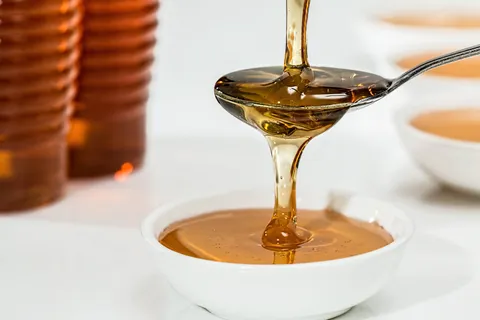Glas Manuka Honig neben einer Bienenwabe – natürliche Stärkung des geschwächten Immunsystems bei Stress