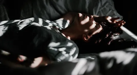 Frau liegt nachts wach im Bett und leidet an Schlaflosigkeit durch Stress