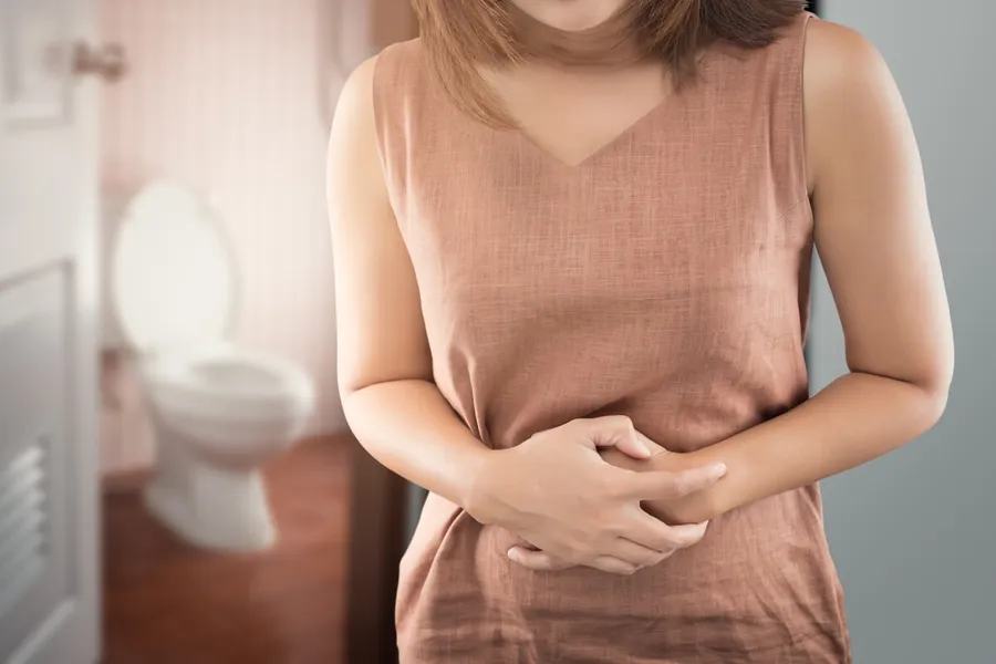 Frau hält sich schmerzend den Bauch – Reizdarmsyndrom durch Stress als häufige Ursache