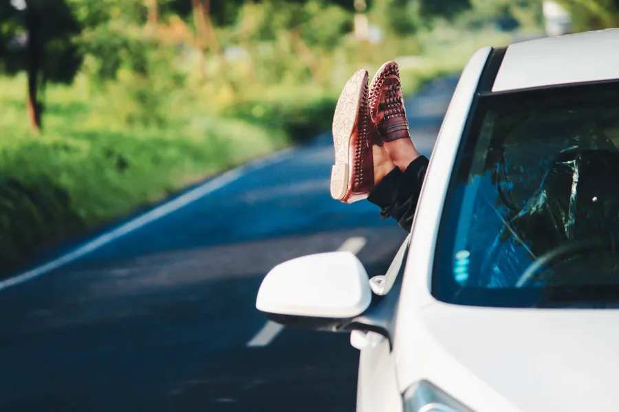 Frau sitzt entspannt am Steuer und praktiziert Stressbewältigung beim Autofahren