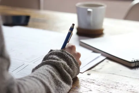 Gestresste Studentin am Schreibtisch mit Büchern – Tipps gegen Stress im Studium