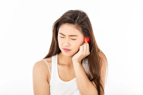Person hält sich die Ohren zu – Tinnitus und Stress als Ursache von Ohrgeräuschen