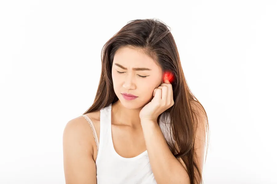 Person hält sich die Ohren zu – Tinnitus und Stress als Ursache von Ohrgeräuschen