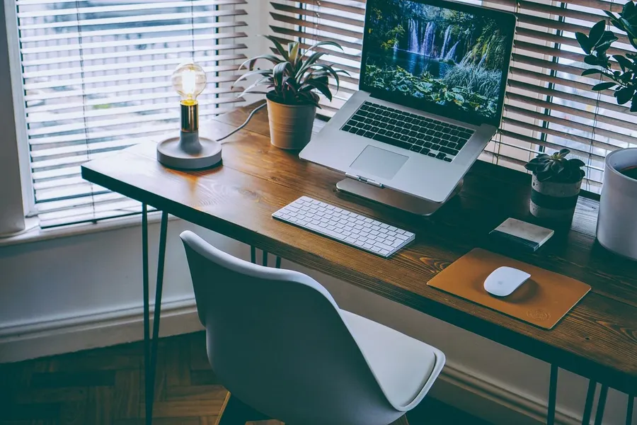 Person arbeitet entspannt im Home-Office am Schreibtisch und reduziert Stress durch Heimarbeit