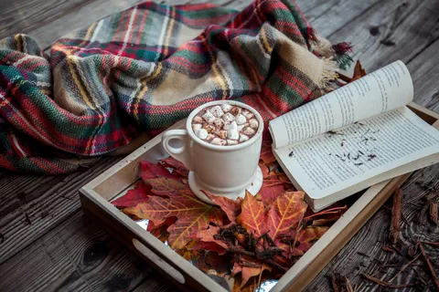 Hygge-Atmosphäre mit Kerzenlicht, Wolldecke und Teetasse gegen Alltagsstress